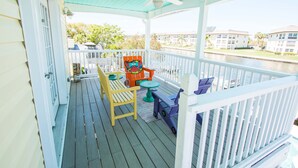 A covered deck with a white railing, a ceiling fan, and a view of a water body and buildings in the background. - A bit of Key West in New Port Richey: Bright Home w/ Pool & Boat Dock Access! (New Port Richey)