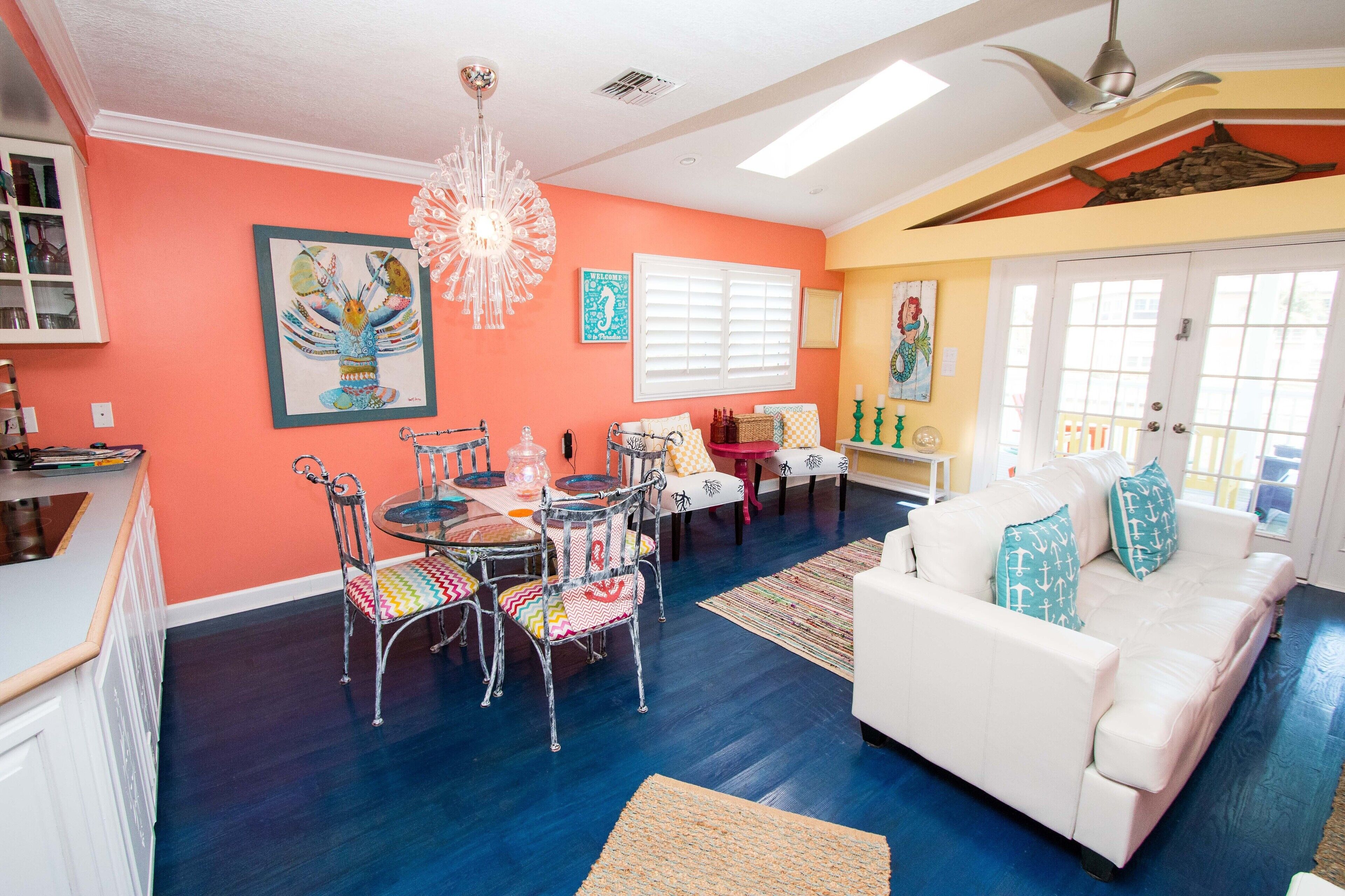 A dining area with a round table and chairs, a white sofa, and a ceiling fan.