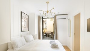Hotelkamer met een bed, een kroonluchter, een kunstwerk in een lijst en uitzicht op het buitengebied.