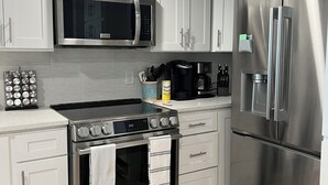 Una cocina moderna con electrodomésticos de acero inoxidable, armarios blancos y un techo con diseño en espiga.