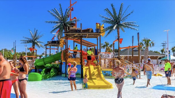 Un parc aquatique avec des toboggans, des palmiers et des personnes qui profitent des installations.