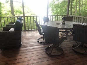A wooden deck with wicker furniture and a round table. - Connestee Falls Lakefront Mountain Home  (Brevard)
