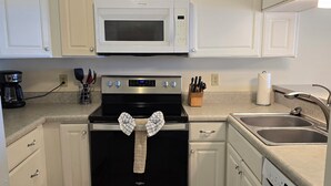 A kitchen with white cabinets, a microwave, an oven, a dishwasher, and a sink. - Beachfront - 2 bedrooms for price of one! (Pensacola)