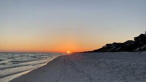 A beach with a sunset, sandy shore, and a building on the right.