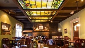 A restaurant with a large stained glass ceiling, wooden tables, and chairs. - Charming Cottage on Main St. in Historic St. Charles! Jetted Tub, 2 Fireplaces!! (St. Charles)