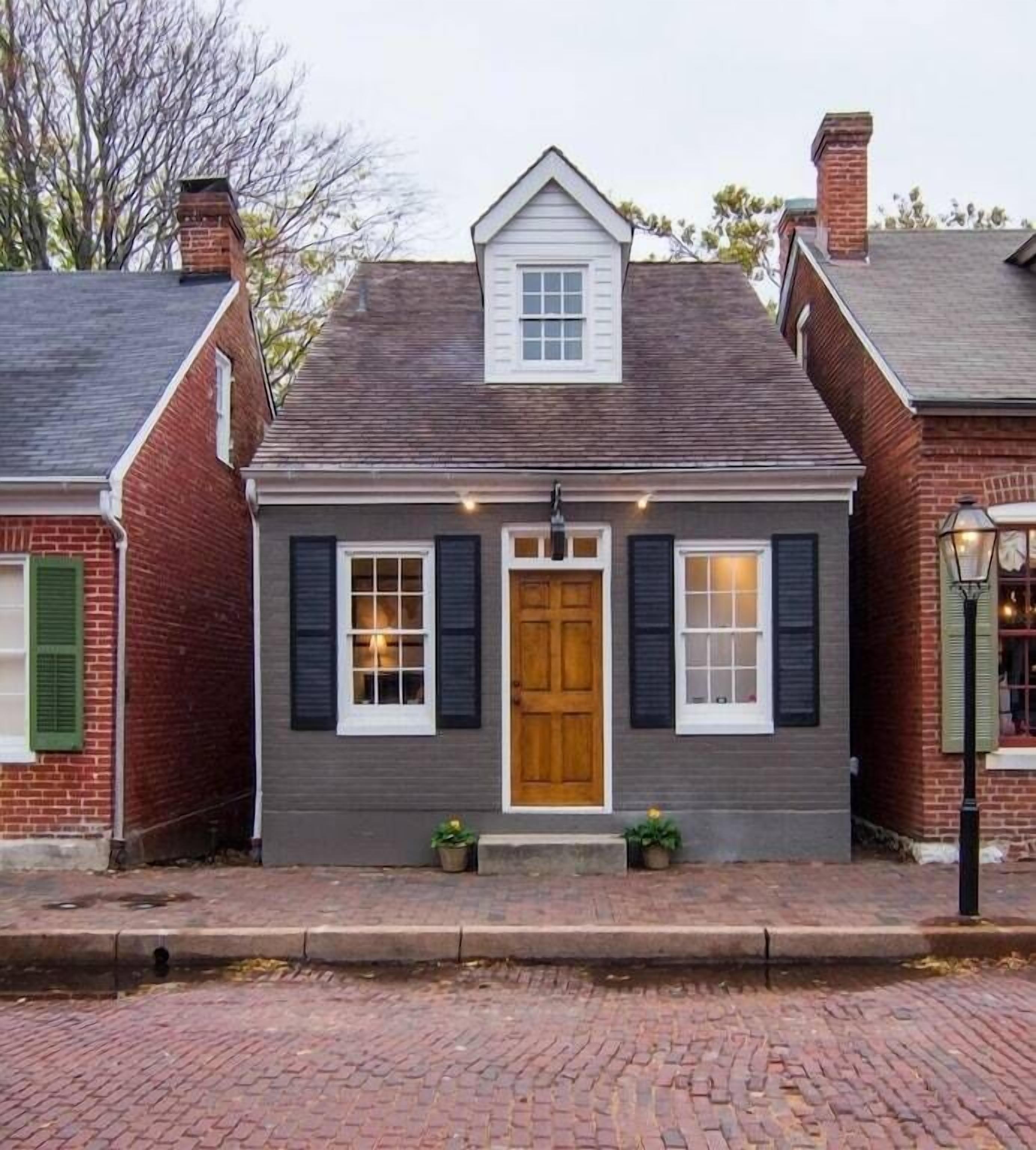 A two-story house with a central entrance, a small porch, and a brick chimney.