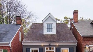A two-story house with a central entrance, a small porch, and a brick chimney. - Charming Cottage on Main St. in Historic St. Charles! Jetted Tub, 2 Fireplaces!! (St. Charles)