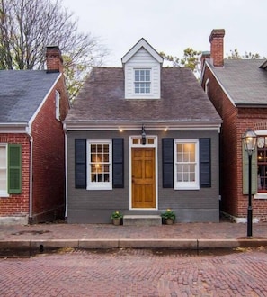 Une maison à deux étages avec une entrée centrale, un petit porche et une cheminée en briques.