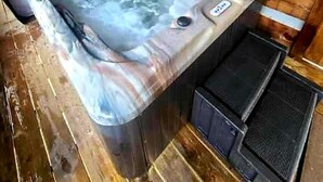Un bain à remous dans un chalet en bois, avec un plancher et des murs en bois.