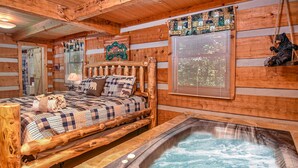 Une chambre de style rustique avec un lit, un bain à remous et des murs en bois.