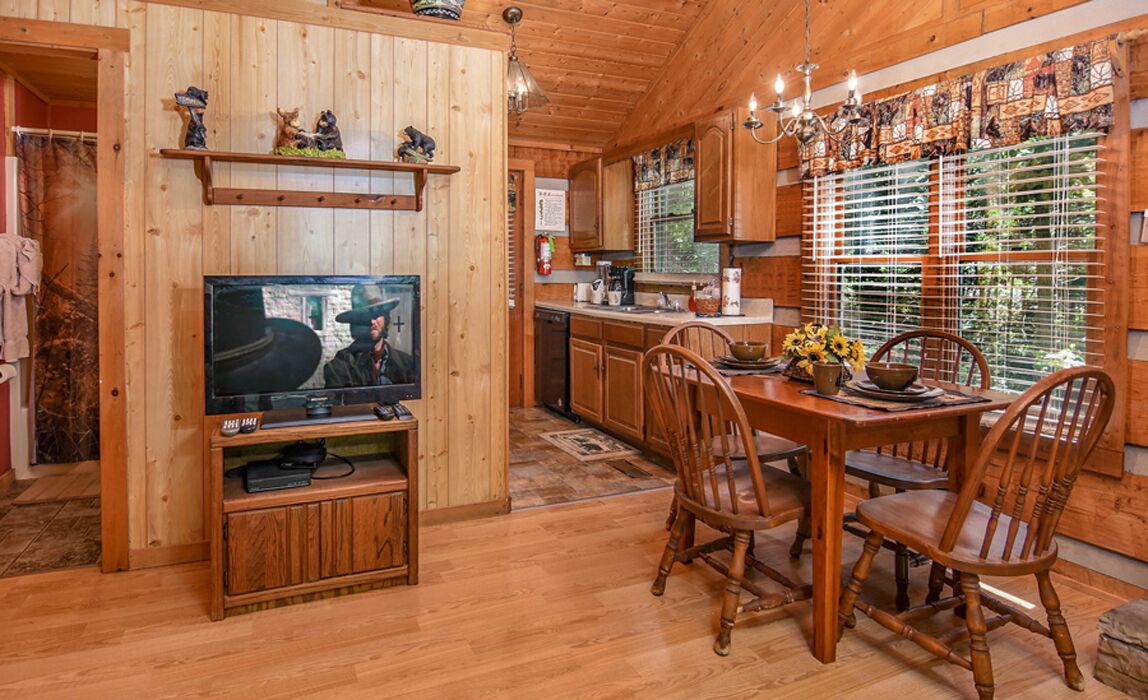 Un intérieur en bois comprenant un coin repas, un téléviseur et une cuisine.