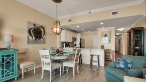 Un coin repas avec une table ronde, des chaises blanches et un buffet de couleur turquoise.