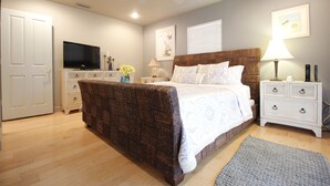 Un dormitorio con cama, televisión, mesita de noche, lámpara y ventilador de techo.