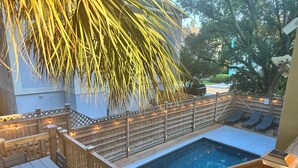 Una terrassa de fusta amb piscina, gandules i llums penjants.