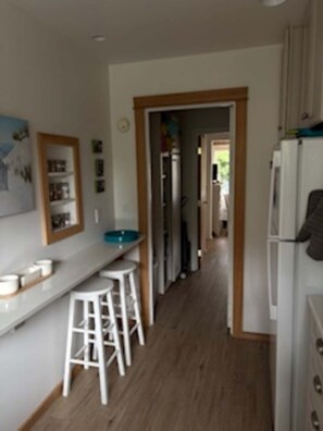 Eine Küche mit weißen Arbeitsplatten, einem Kühlschrank und Holzboden.