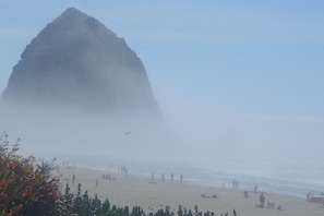 Ein Strand mit einer großen Felsformation im Hintergrund.