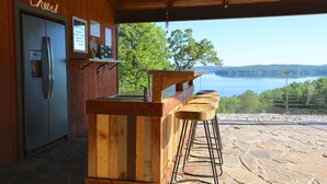 Un comptoir en bois, doté de tabourets et d’un réfrigérateur, offrant une vue imprenable sur un magnifique lac.