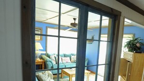 Una habitación con un ventanal grande, un ventilador de techo y una pared azul.
