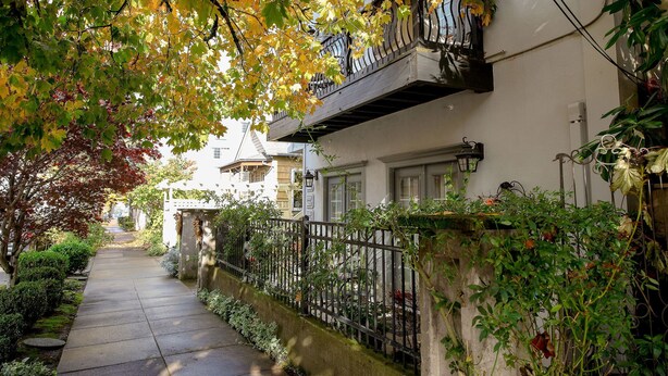 Un estrecho sendero urbano bordeado por edificios con balcones y una valla.
