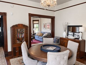 A dining area with a round table, chairs, a chandelier, and a bookshelf. - Victorian with Modern Comforts in NW Portland. Driveway Parking. Walk to it all! (Portland)
