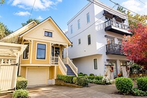 A two-story residential building with a front porch, a garage, and a small garden. - Victorian with Modern Comforts in NW Portland. Driveway Parking. Walk to it all! (Portland)