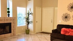 Ein geräumiges Wohnzimmer mit Kamin, Deckenventilator und großem Fenster.