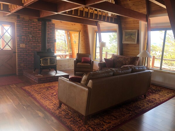 A cozy living room with a fireplace, leather sofa, and a patterned rug. - A Grandview over Capitol Reef National Park (Torrey)