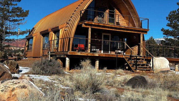 A wooden cabin with a large balcony and a staircase leading to the upper level. - A Grandview over Capitol Reef National Park (Torrey)