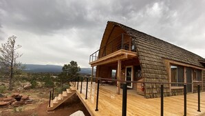 A wooden cabin with a balcony, a staircase leading to the deck, and a view of the surrounding landscape. - A Grandview over Capitol Reef National Park (Torrey)