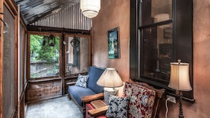 A cozy room with a wooden bench, a red sofa, and a blue couch. There is a window with a view of greenery outside.