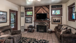 A living room with a fireplace, a television, and a large rug.