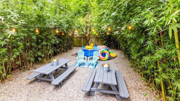 A garden area with bamboo plants, picnic tables, and a hot tub with inflatable rings. - Michou's Marigny Historic Gem | Historic Getaways (New Orleans)