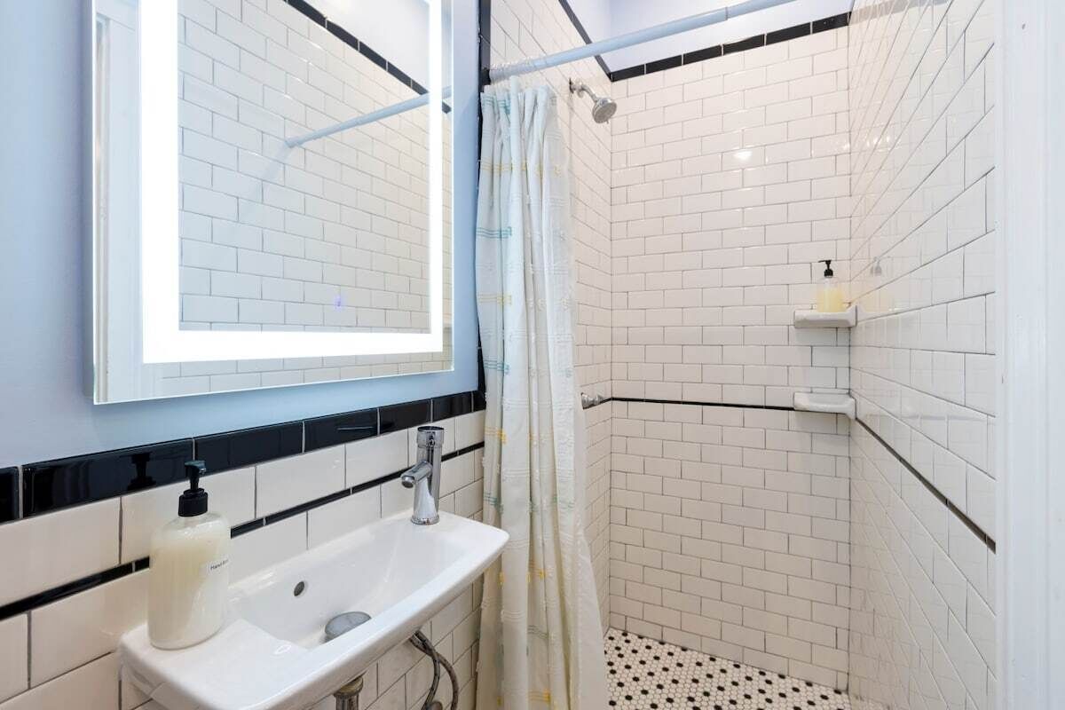 A bathroom with a white sink, a mirror, and a shower area with a curtain.