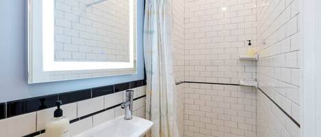 A bathroom with a white sink, a mirror, and a shower area with a curtain.