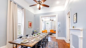 A dining area with a long table set for six, a ceiling fan, and a patterned rug. - Michou's Marigny Historic Gem | Historic Getaways (New Orleans)