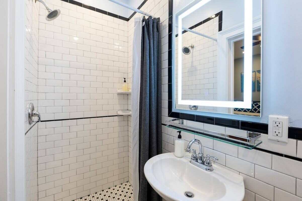 A bathroom with a shower, a sink, and a mirror.