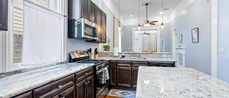 A kitchen with dark wooden cabinets, a stainless steel range, and a granite countertop.