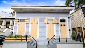 A two-story house with a front porch, a small garden, and a mailbox. - Michou's Marigny Historic Gem | Historic Getaways (New Orleans)