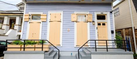 A two-story house with a front porch, a small garden, and a mailbox.