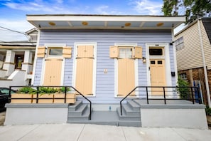 A two-story house with a front porch, a small garden, and a mailbox.