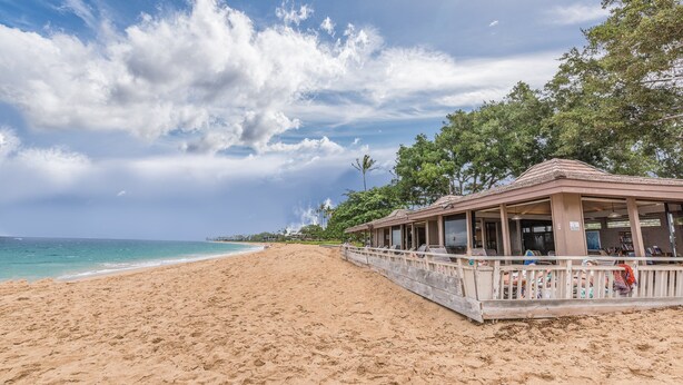 Una spiaggia con una struttura in legno, probabilmente una casa o un padiglione sulla spiaggia, con una ringhiera e vista sull'oceano.