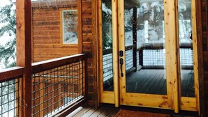 A wooden cabin with a covered porch and a glass door leading to a deck. - Newer Built ski to ski lift , Extra Master Bedroom ,Sleeps 10 (Homewood)
