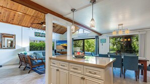Una cocina amplia con una isla grande, techo de madera e iluminación colgante moderna.