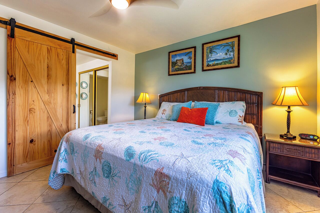 Une chambre à coucher avec un grand lit, deux lampes fixées au mur et une porte en bois.