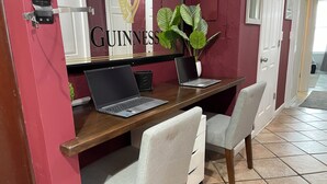 A workspace with two laptops, a potted plant, and a 'GUINNESS' sign on the wall.