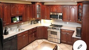 A kitchen with wooden cabinets, stainless steel appliances, and a tiled floor.