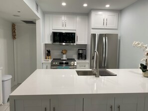 A modern kitchen with white cabinets, stainless steel appliances, and a central island.