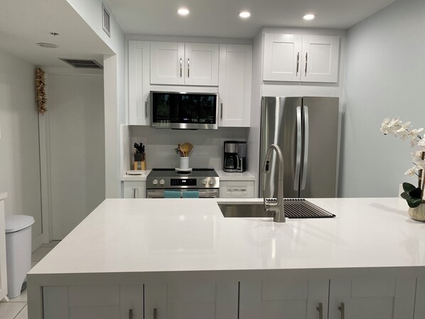 A modern kitchen with white cabinets, stainless steel appliances, and a central island.