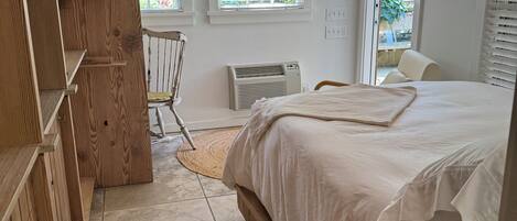 A bedroom with a bed, wooden wardrobe, and a chair.