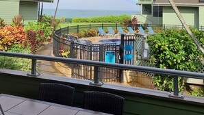 A pool area with lounge chairs, a fenced deck, and a view of the ocean. - Experience paradise at Kahana's beachfront 3-bedroom condo near Kaanapali Beach  (Lahaina)